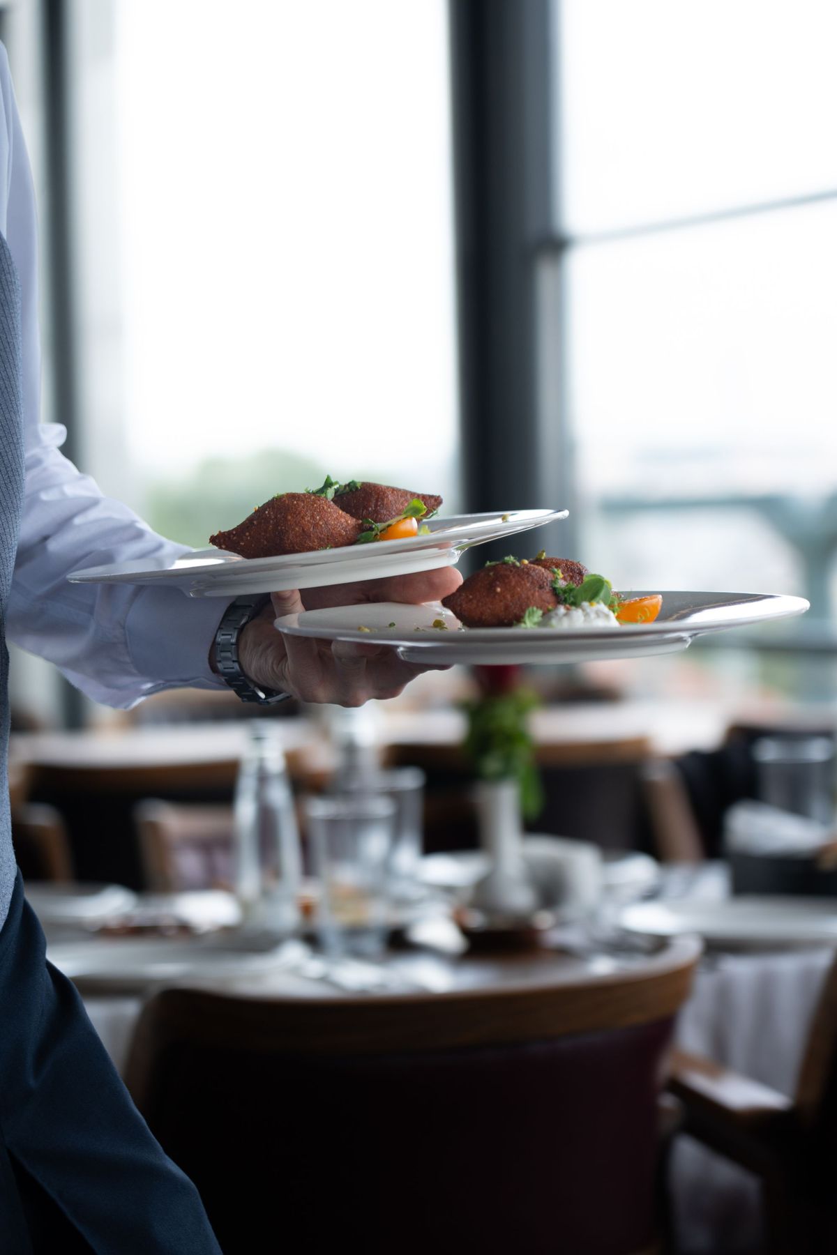 A team member serving dishes to guests at a table